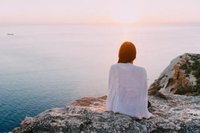 pexels-photo-185801 woman sitting on gray rock near body of water